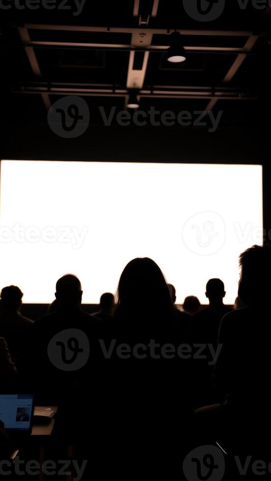 Silhouettes of people watching a blank screen photo