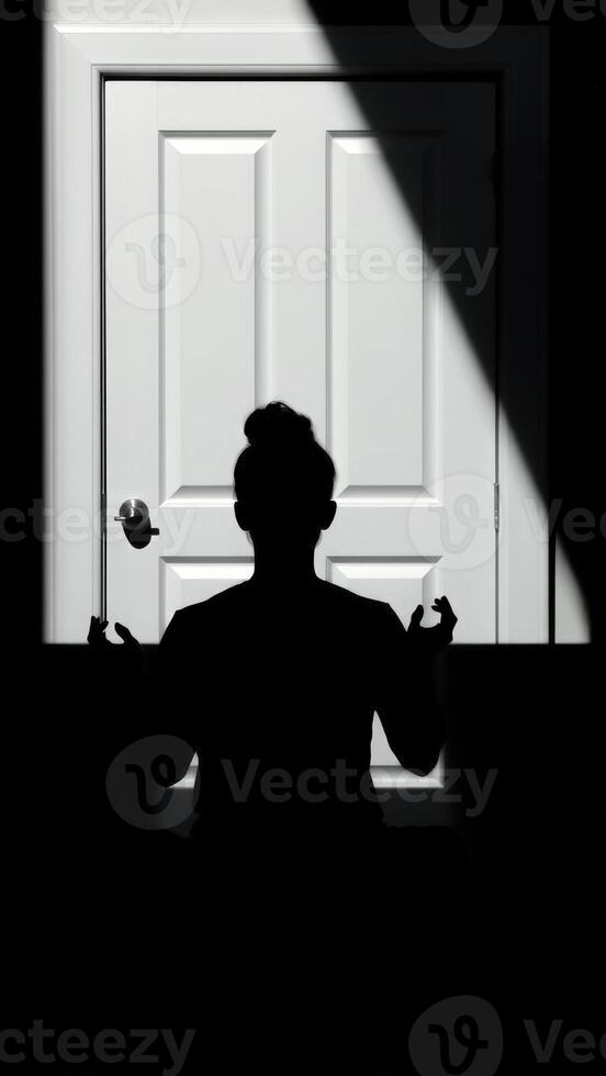Silhouette of a person reaching towards a closed door photo