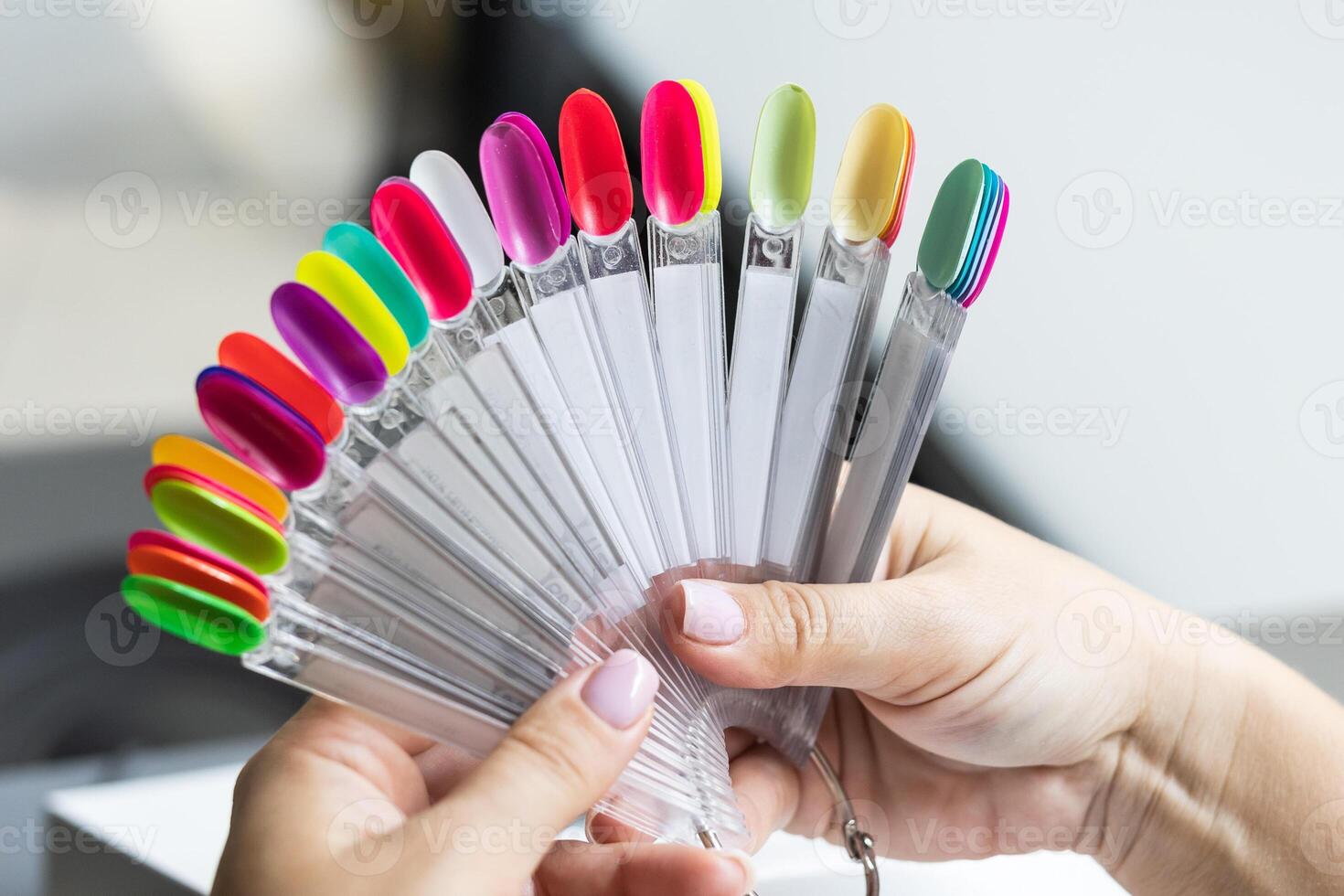 Collection of nails color polish samples. A palette of nail designs of different colors with gel polish. Transparent tips with nail polish samples. Demonstration fan-shaped palette of color shades. photo