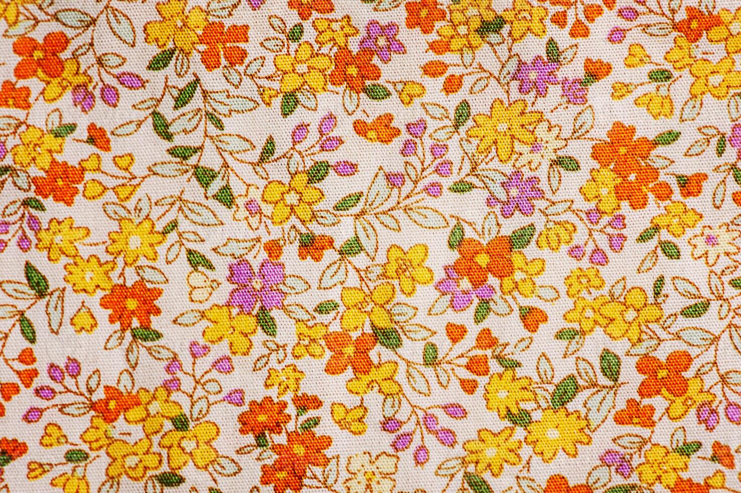 The fabric is beige with a flower of orange, yellow and purple as a background photo