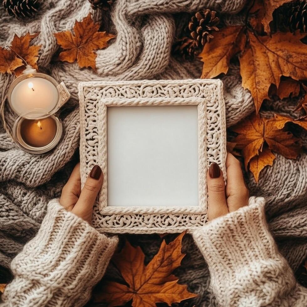 Wooden frame surrounded by autumn leaves and pinecones on a rustic wooden surface photo