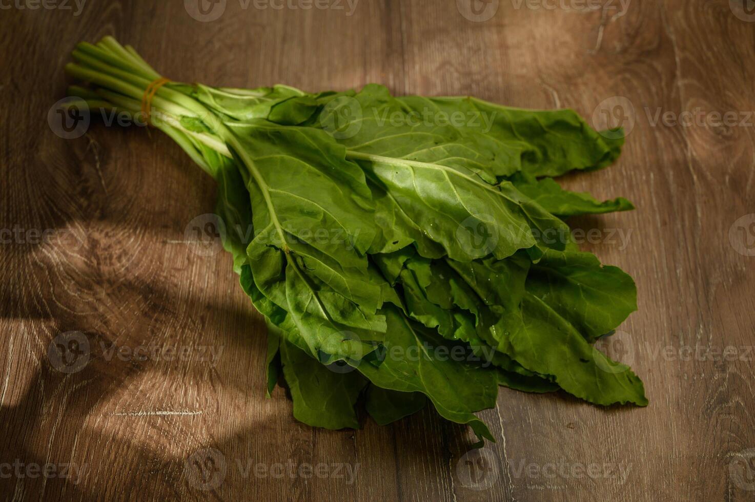 Spinach leaf on wooden background in rays of light photo