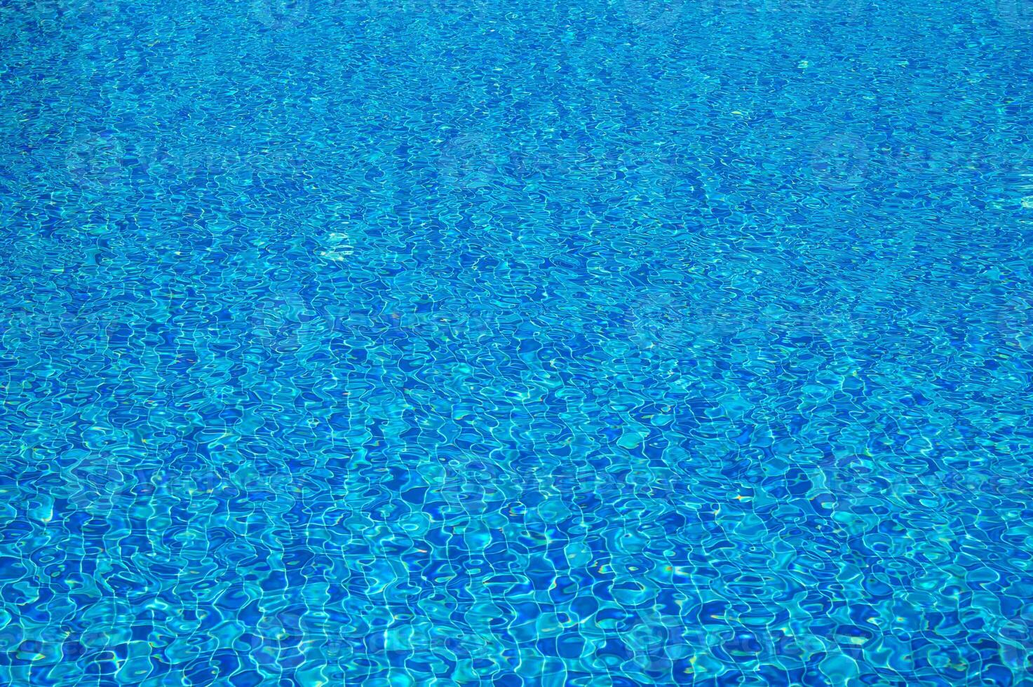 Blue water texture with light reflection. Water surface with rings and ripples, splashes and bubbles photo