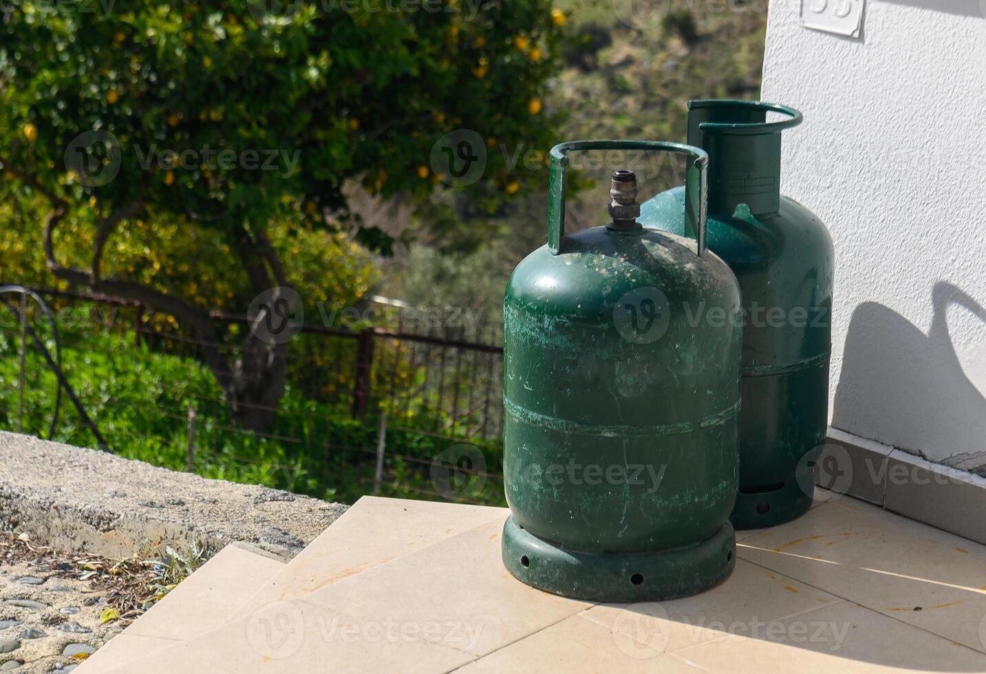 green propane cylinders near the exterior stone wall of an old house photo