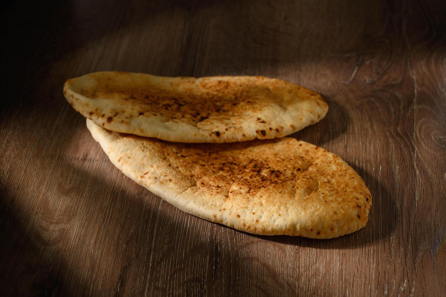 Freshly baked pita bread or flatbread on wooden background. photo