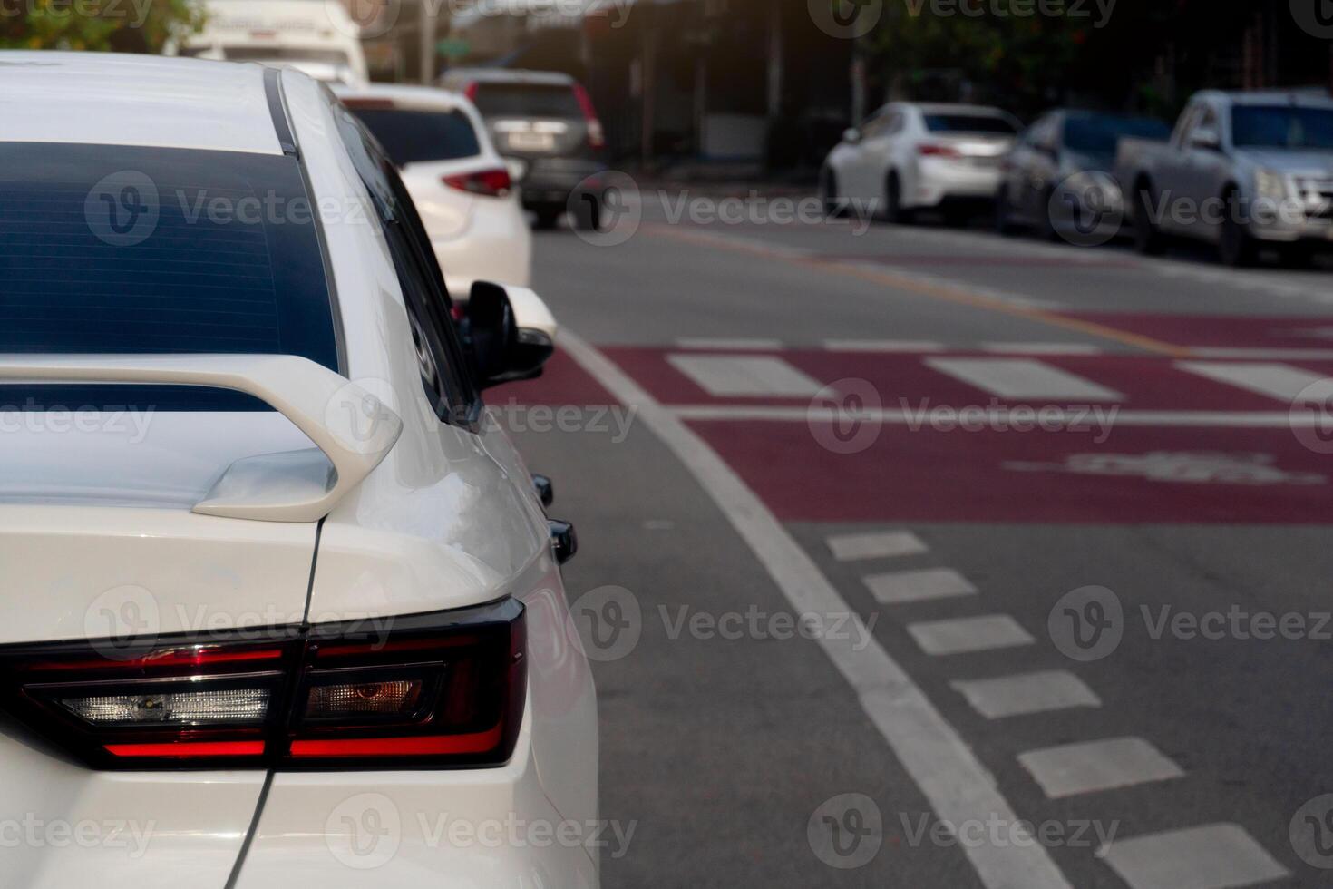 Tail lights of white car parking beside road. Road with traffic lines for safety when crossing roads in the city. photo