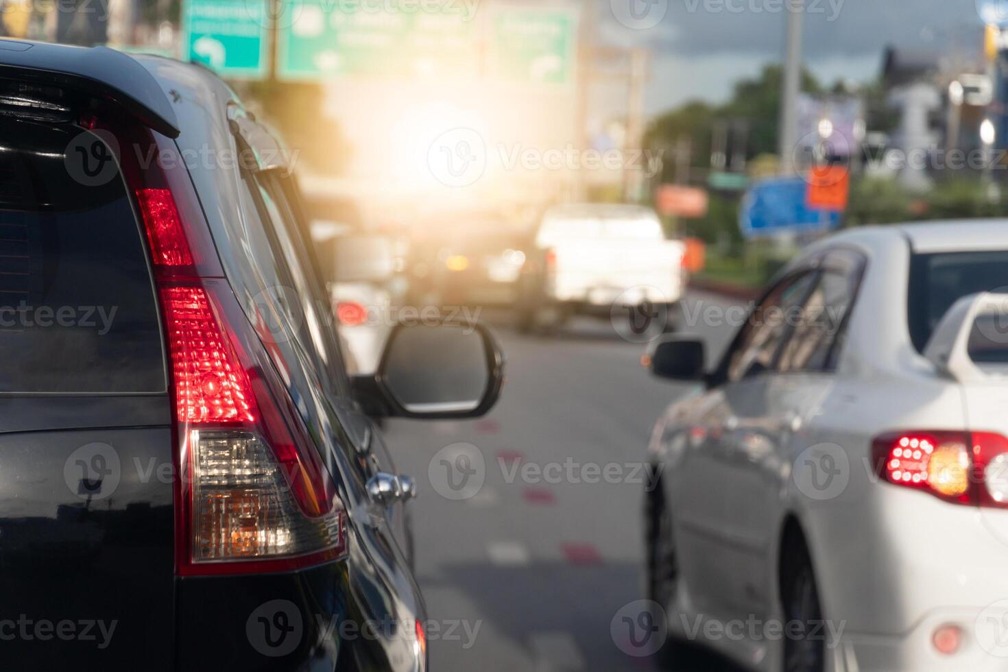 Rear side of black car on the aspahlt road. Transtport of car turn on brake light in the business time environment of moring time. Traffic congestion and queues of cars. photo