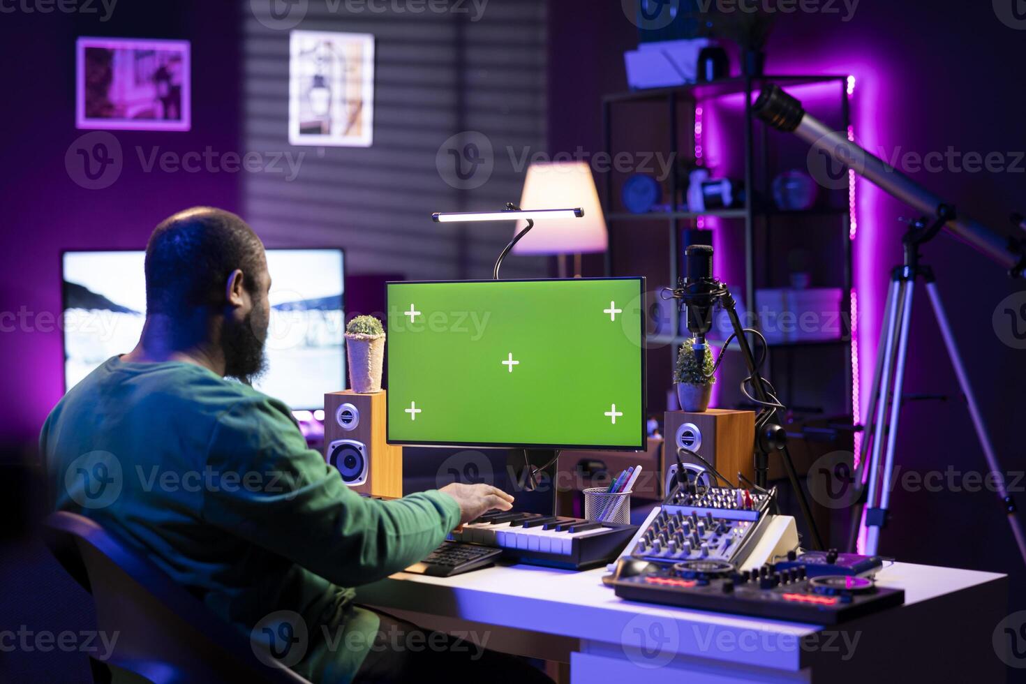 Artist plays midi controller synthesizer next to greenscreen layout, working on producing new music with his audio musical instruments in home studio. Musician using isolated copyspace. photo
