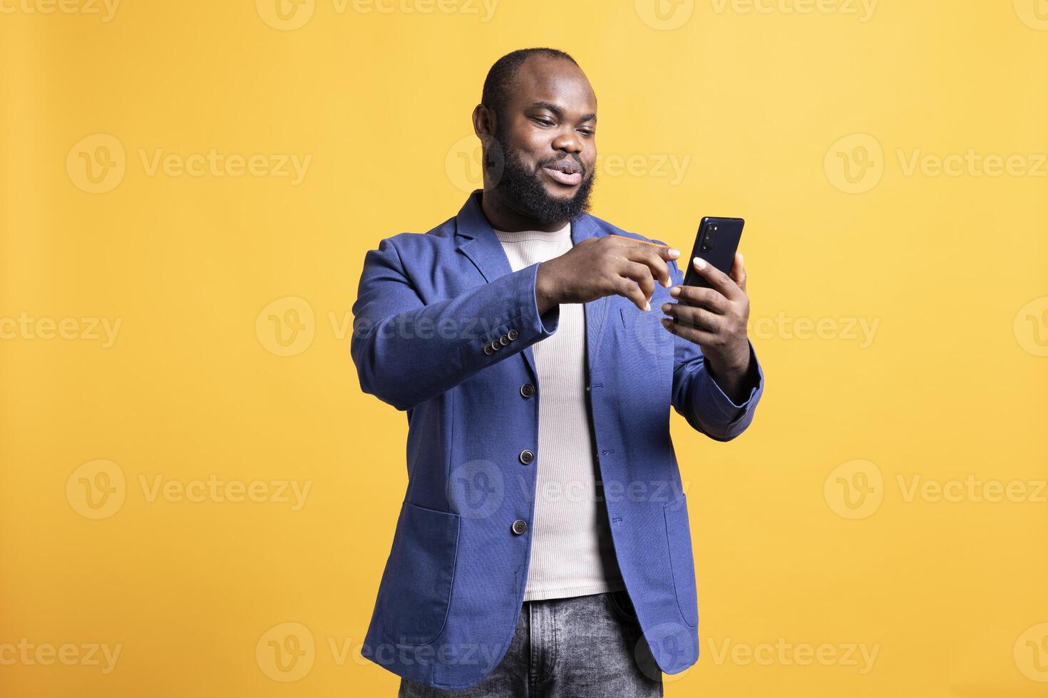 Shoppaholic african american man adding payment method on smartphone, studio background. Smiling BIPOC person does online shopping, typing credit card information on mobile phone photo