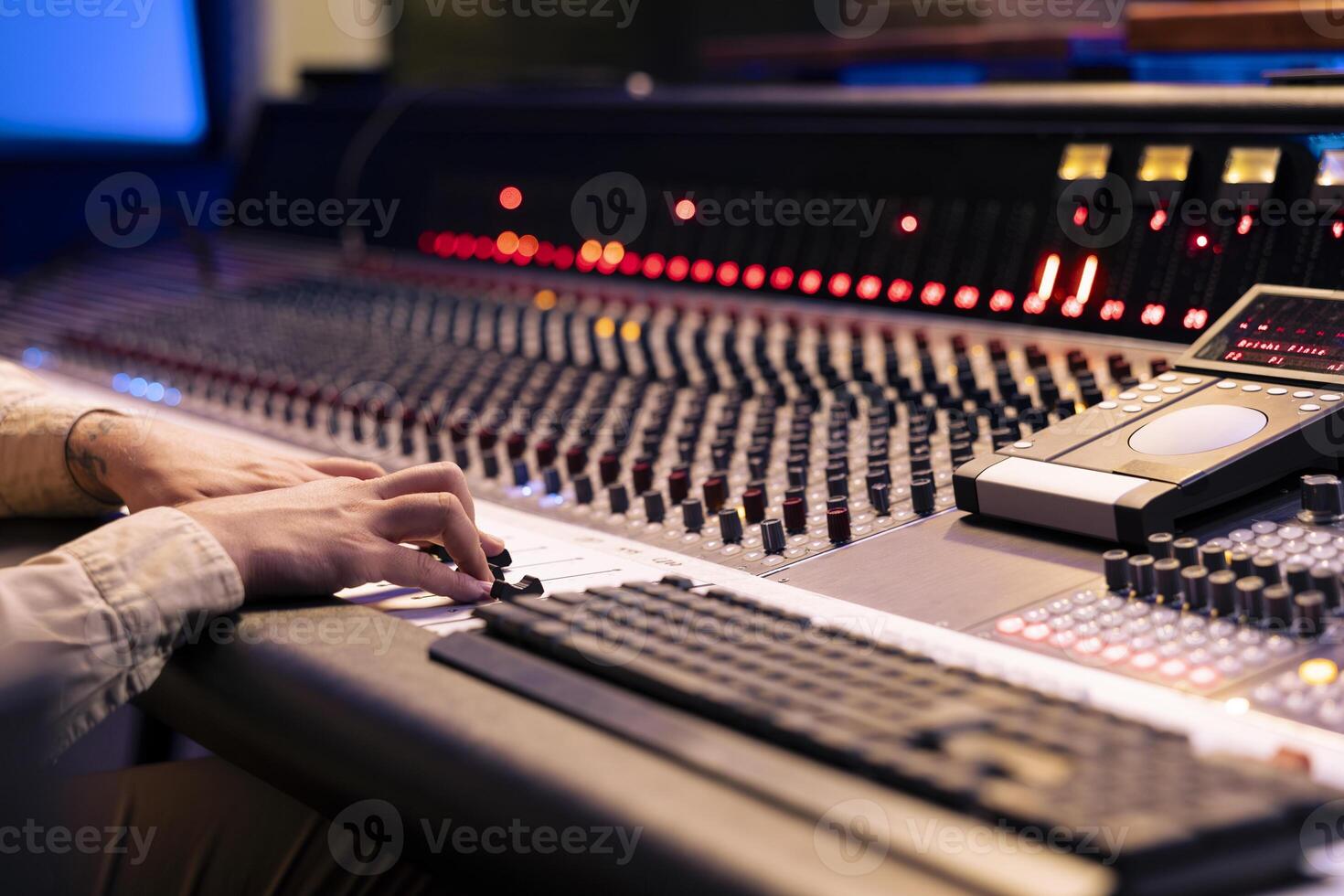 Audio engineer twisting pre amp knobs and switchers on panel board in control room, using mixing console for editing and mastering music. Professional skilled producer in music studio. photo