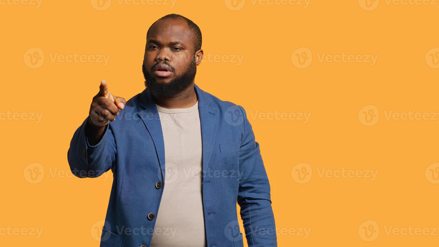 Angry african american man fighting with friend over debacle, isolated over studio background. Rude person in disagreement with mate, swearing and pointing finger, camera A photo