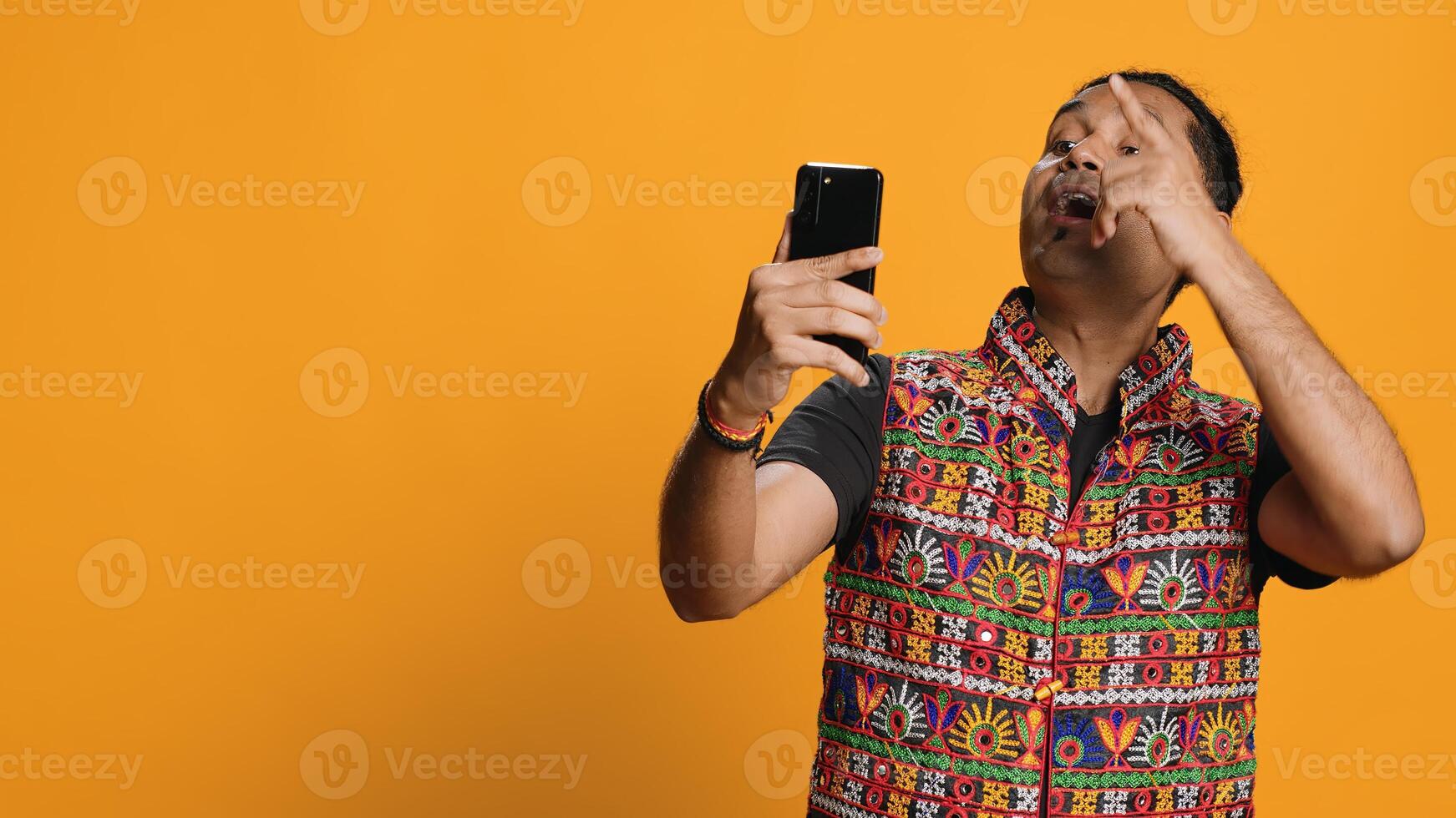 Happy man chatting with friend over online videocall on smartphone, doing friendly gestures. Smiling person communicating with mate on teleconference using mobile phone, studio background, camera A photo