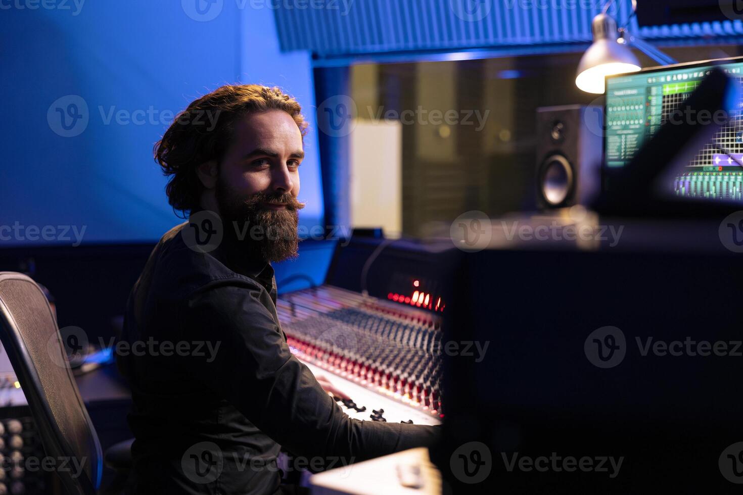 Portrait of sound designer working with mixing console and daw software on pc in professional studio, producing tracks for a pop album. Talented producer editing new music in control room. photo