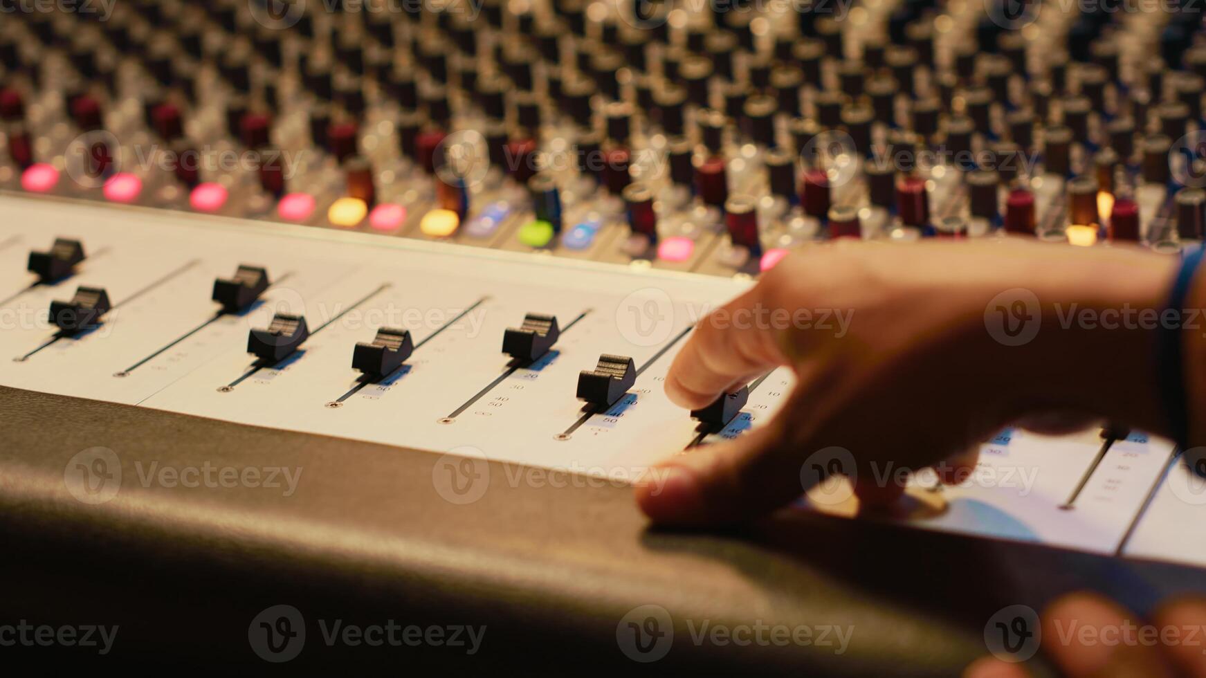 Artist composer creating a new song on his electro guitar in studio, recording tracks in control room using mixing console and amplifier. Songwriter creates new music for his album. Camera A. photo