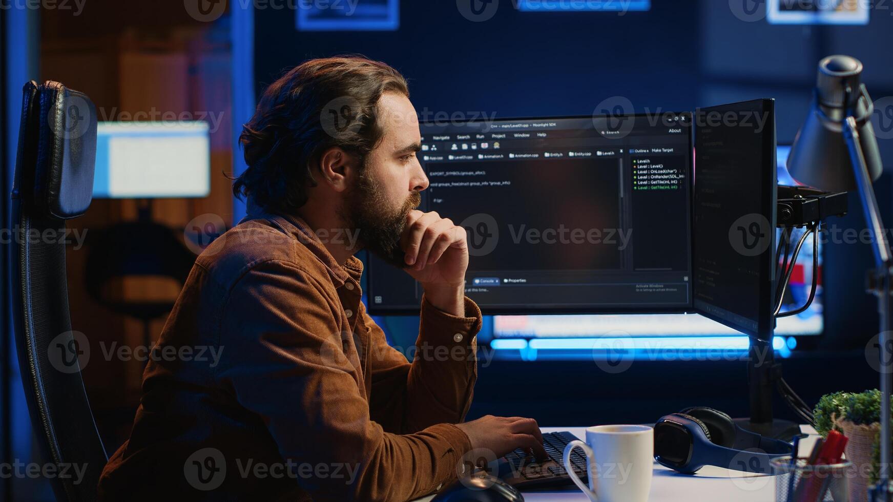 Programmer doing web development during remote job shift in neon lit home office, finishing coding project. IT specialist sitting at computer desk, working on desktop PC, camera A photo