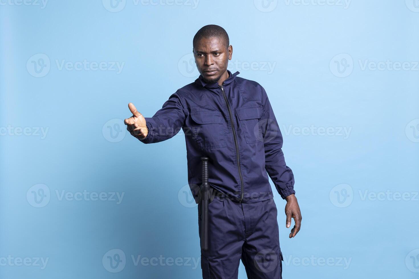 African american security agent indicating the direction for persons, working as a patrol officer against blue background. Bodyguard pointing at an access way to the left or right sides. photo