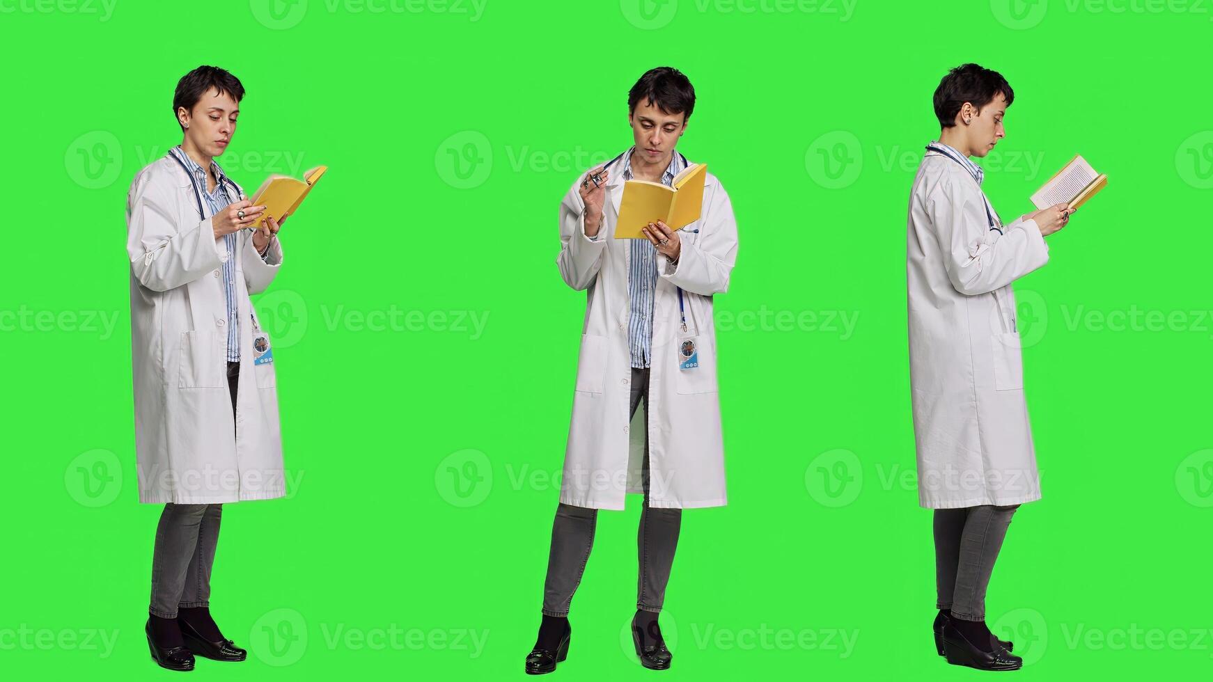Medic specialist reading a healthcare literature book to develop her medical expertise in the industry, stands against greenscreen backdrop. Clever doctor in white coat enjoys lecture. Camera A. photo