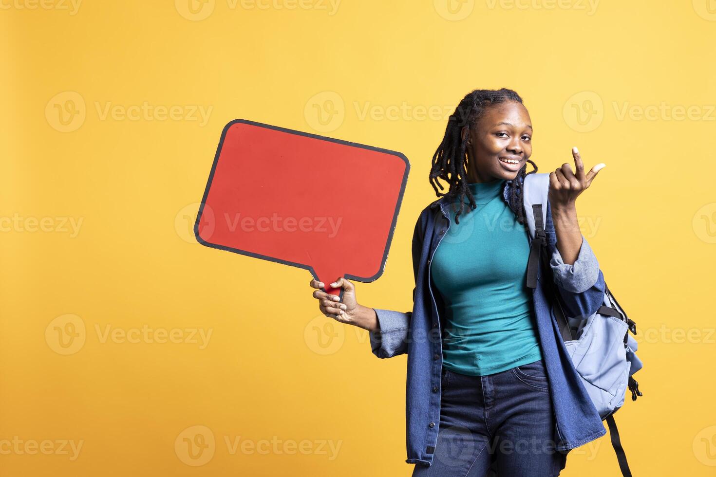 Jolly BIPOC girl holding red speech bubble sign of empty copy space for message. Smiling african american person presenting thought bubble cardboard used as promotion concept, studio background photo