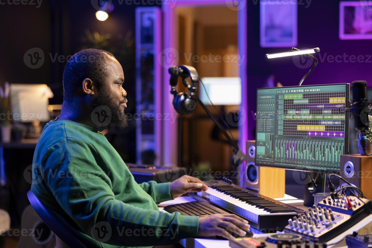 African american composer creating a new track for a project, using professional production pc interface in his home studio. Creative artist songwriter producing music with sound effects. photo