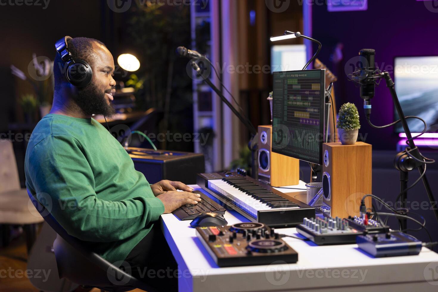 African american producer mixing sounds and tunes on his audio files, listening to the final product on headset. Audio technician works on pc with DAW software interface and stereo equipment. photo