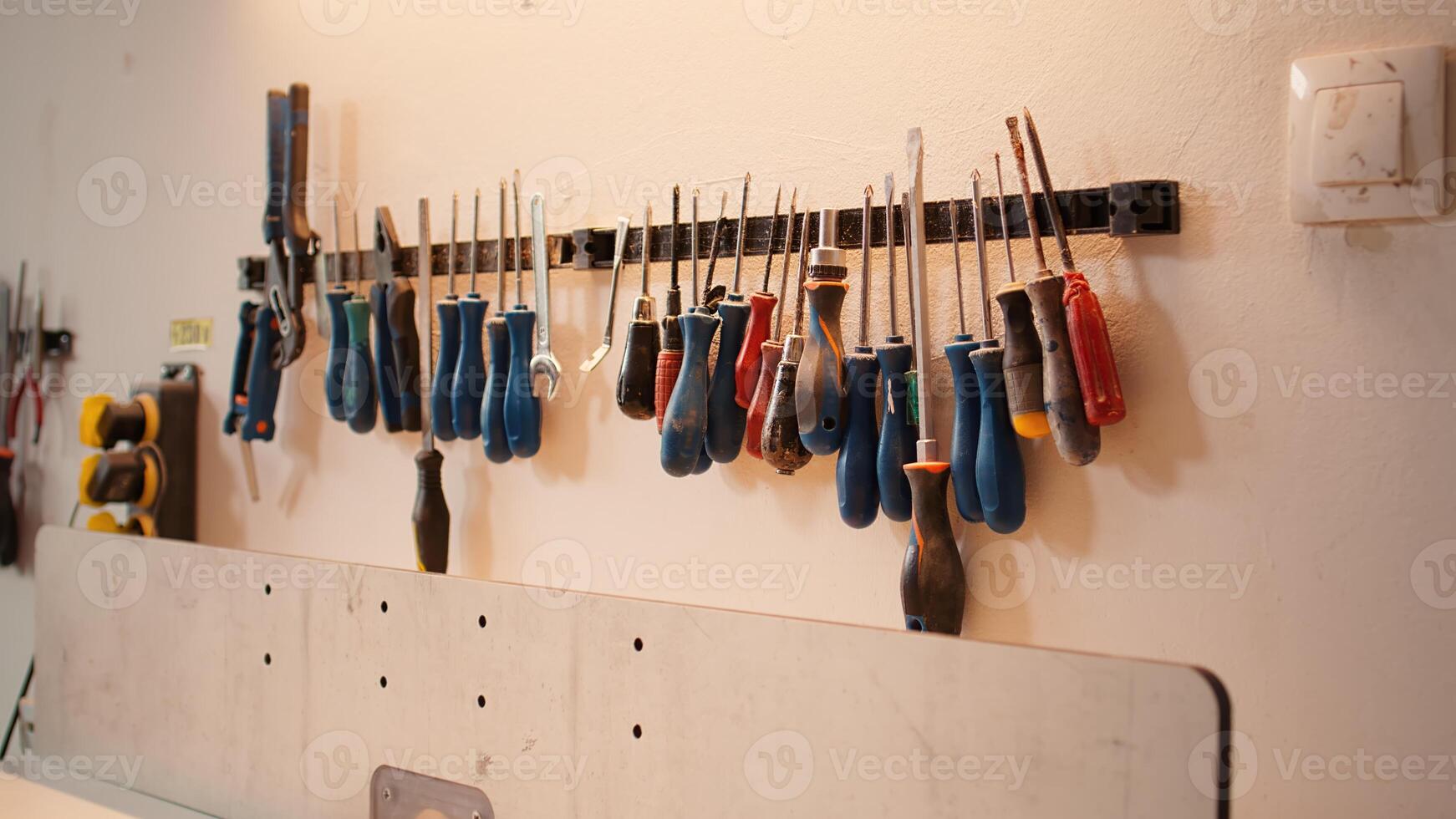 Chisels, screwdrivers, wrench and pliers on wall in furniture assembly shop used for carving wood surfaces. Close up of woodworking gear on rack in carpentry studio, panning shot photo