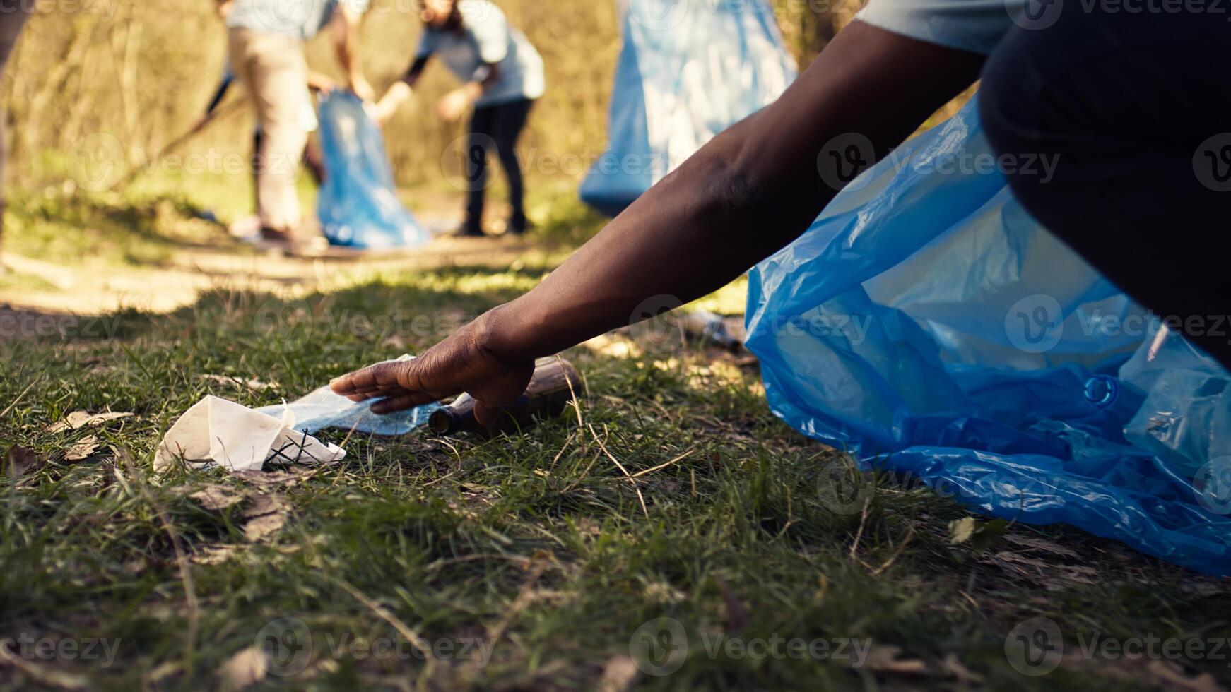Citizens reducing pollution and illegal disposal by tidying the environment and recycling plastic with the right instruments. Volunteers clearing garbage from the forest. Close up. Camera B. photo