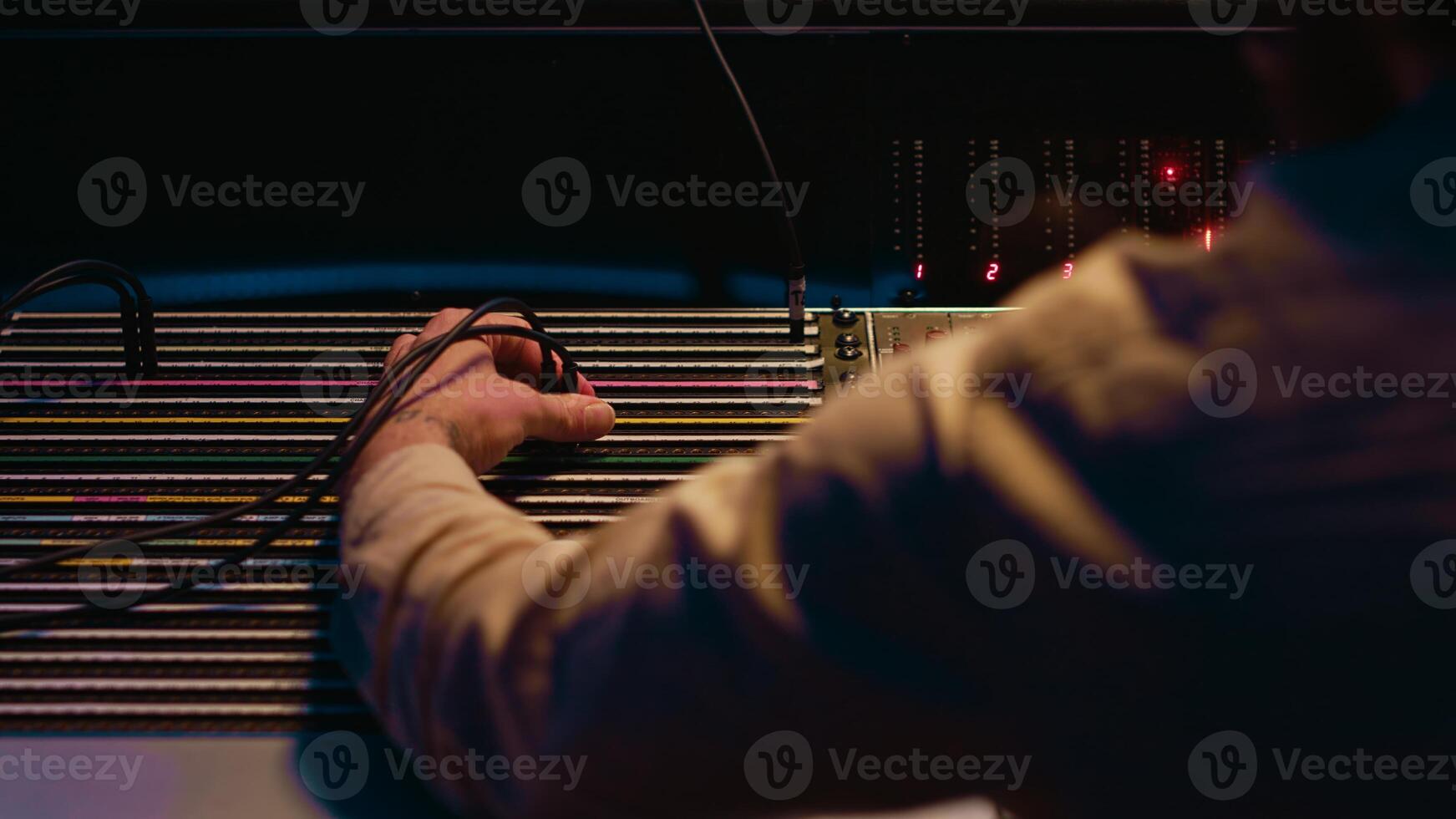 Music producer fixing coiled cable inside amplifier or audio compressor, prepares control room technical equipment for a recording session. Sound engineer works on producing tracks. Camera A. photo