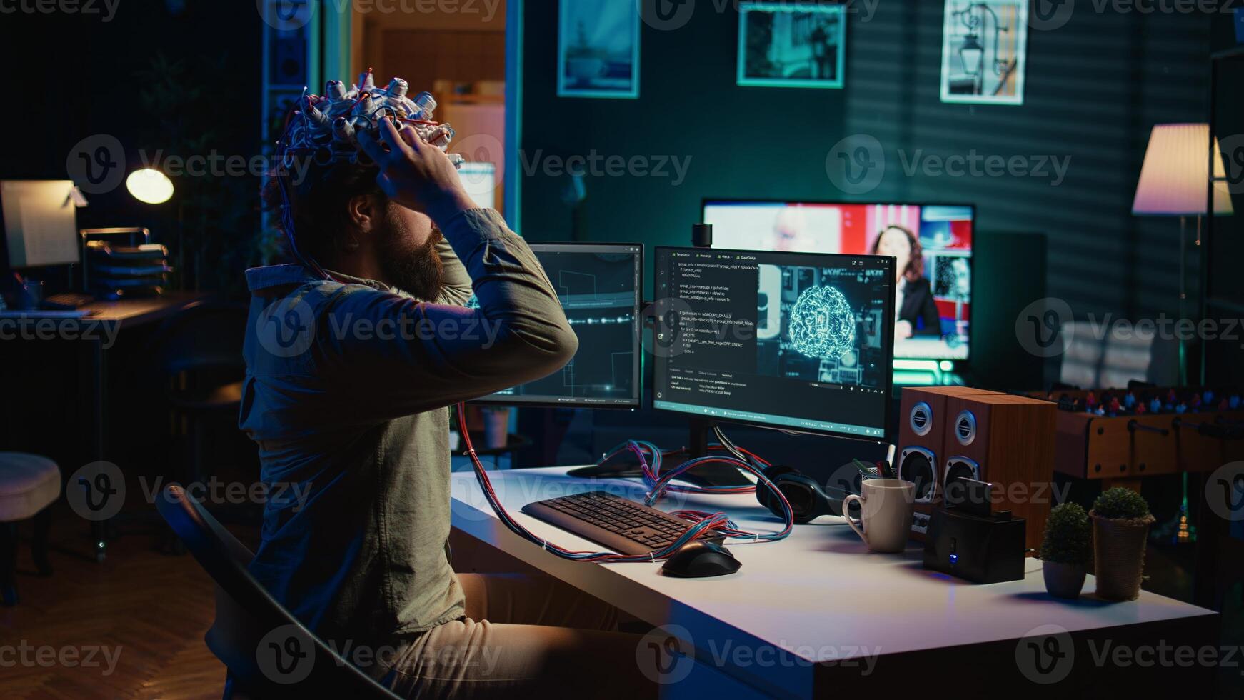Man puts EEG headset on to transfer mind into computer virtual world, becoming one with AI superintelligence. Engineer using futuristic neuroscientific technology to transfer consciousness, camera B photo