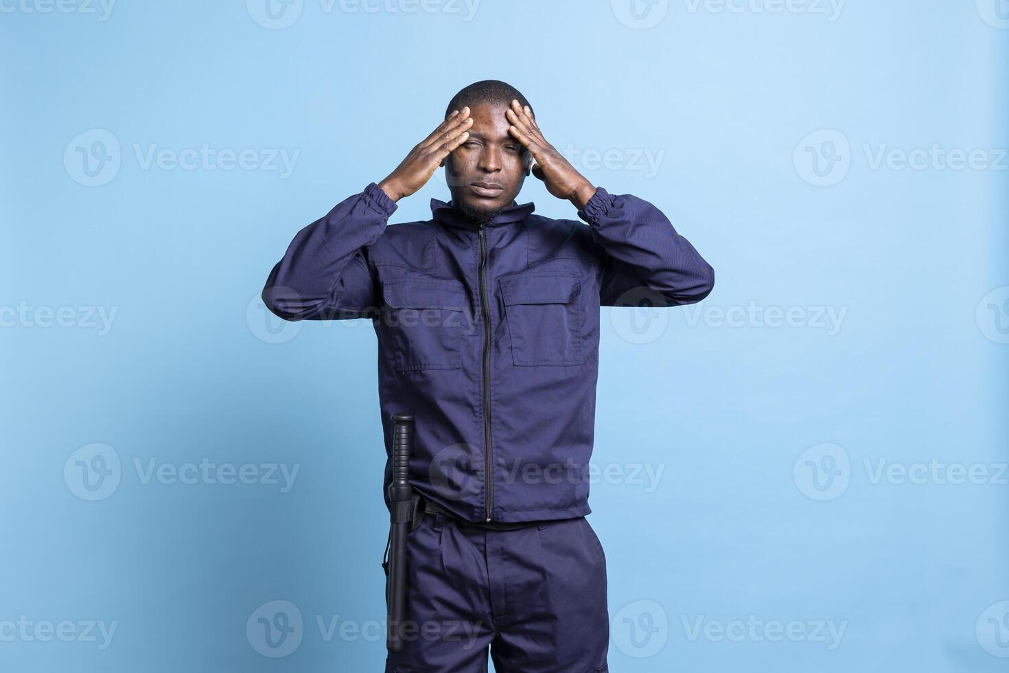 Gloomy anxious security guard having a headache while on duty, feeling under pressure and suffering from sickness. Distraught agent with migraine, unhappy with flu symptoms in studio. photo