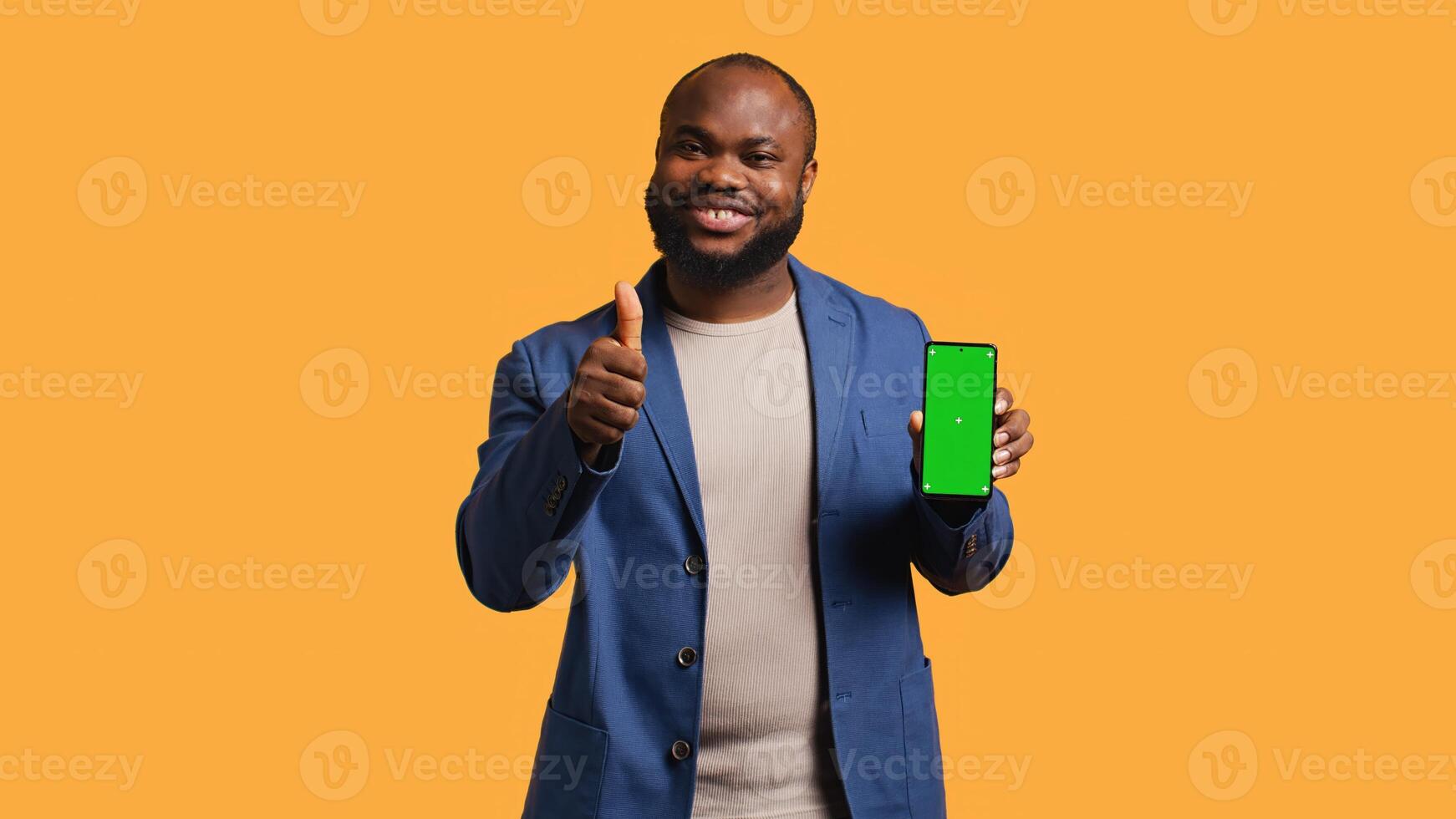 Happy african american man holding green screen phone, doing recommendation. Cheerful BIPOC person presenting mockup device, giving thumbs up sign, studio background, camera B photo