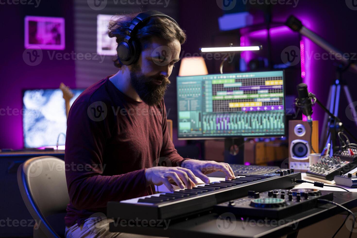Musician playing electronic keyboard piano in his home studio, using daw software on pc and his mixing console to produce tracks. Young artist plays midi controller synthesizer, music industry. photo