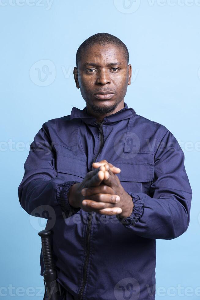 African american agent pointing an imaginary pistol in front of the camera, mimicking target shooting practice. Portrait of security guard holds his hand in the shape of a firearm. photo