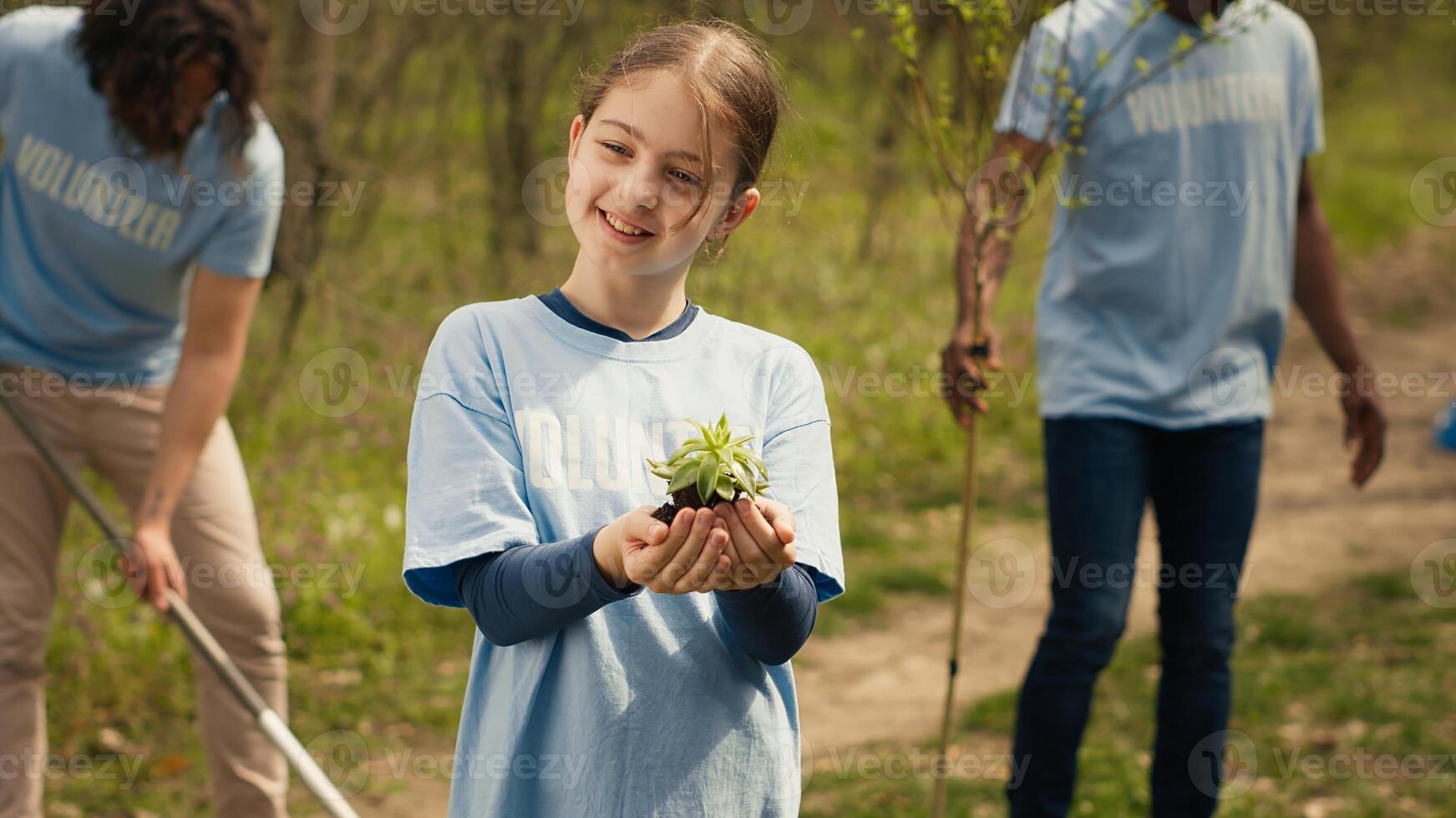 Little girl holding a small green sprout with natural soil in order to preserve forest habitat and protect the ecosystem. Child growing up with a dedication for environmental protection. Camera A. photo