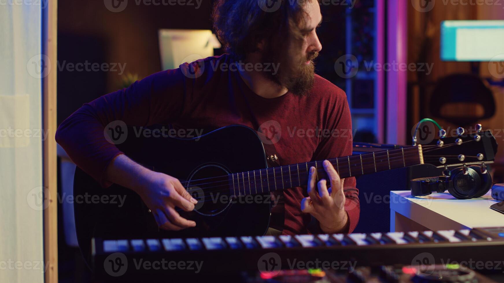 Artist working with daw software at his home studio to record new music on mixing console and soundboard, audio engineering. Musician playing song on guitar and adjusting volume. Camera A. photo