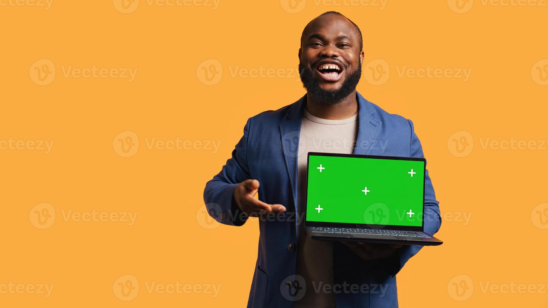 Smiling man holding isolated screen laptop, doing recommendation, talking with viewers. Cheerful BIPOC person pointing towards chroma key notebook, studio background, camera B photo
