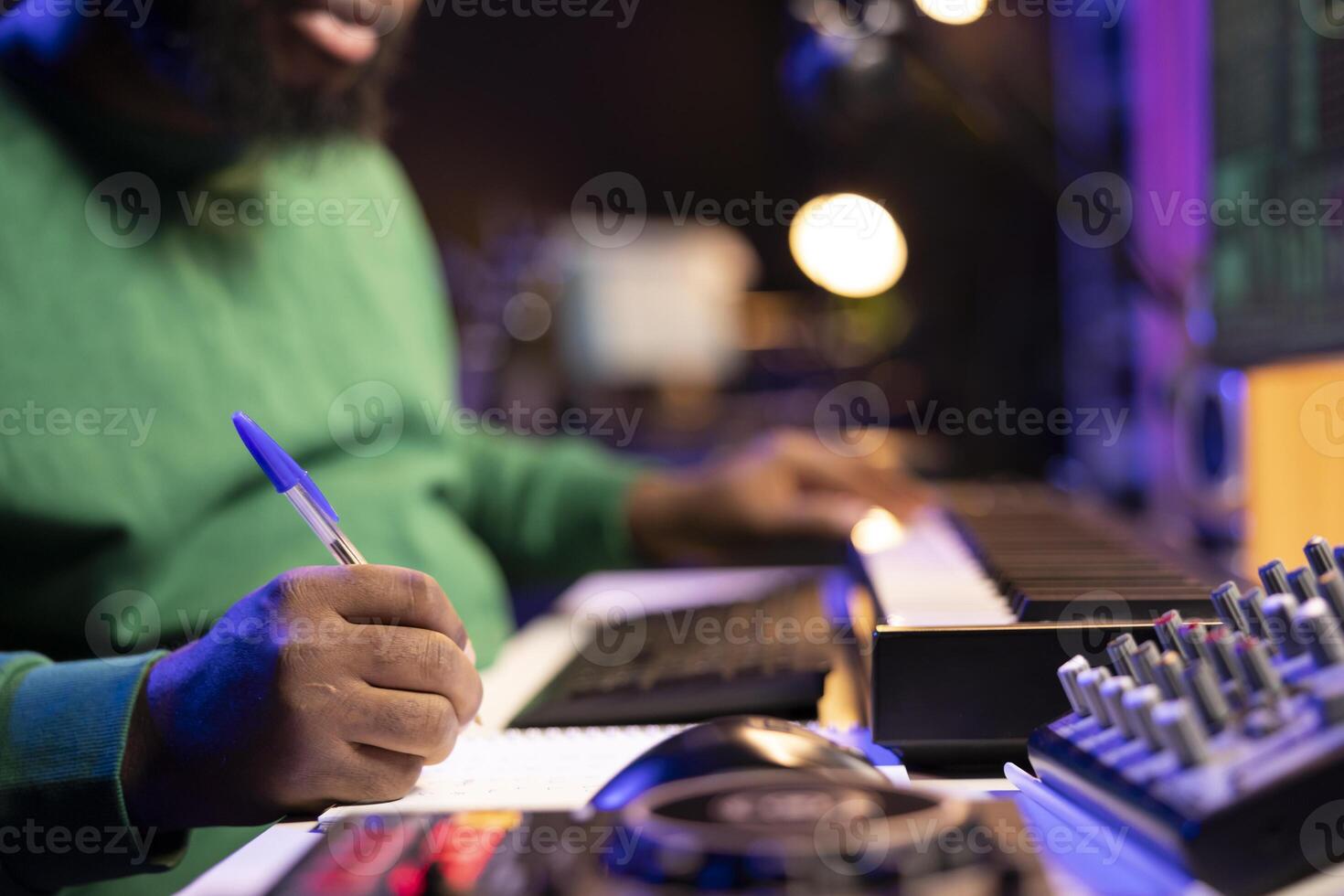 Songwriter taking notes to create new tracks for an album in his home studio, writing lyrics and harmonic elements before recording his song and editing on software, acoustical engineering. photo