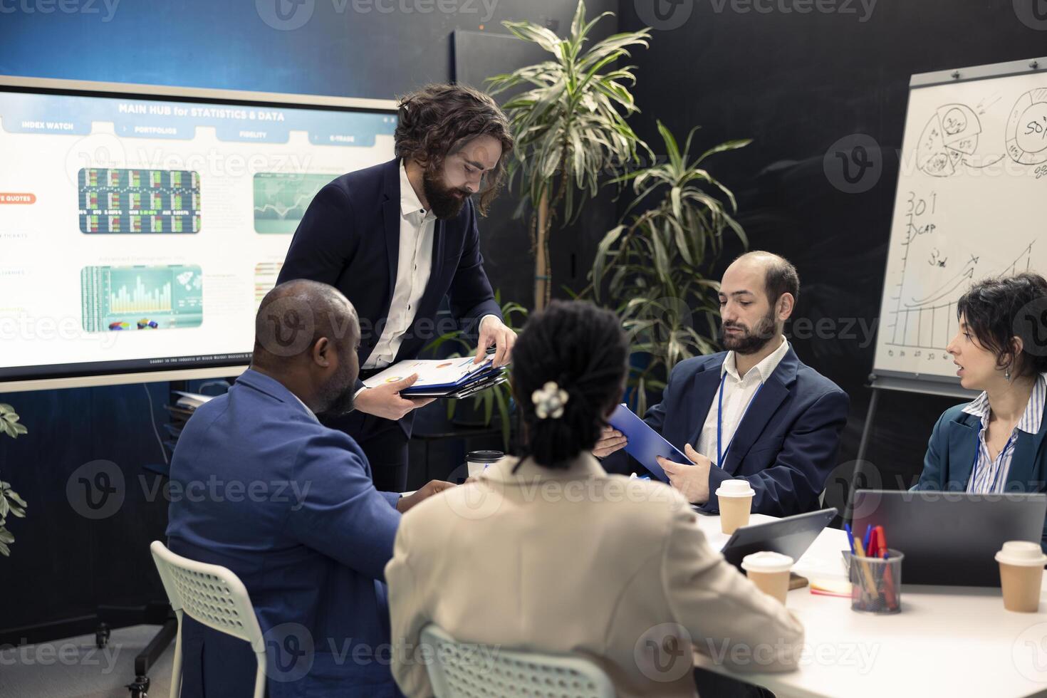 Diverse business colleagues examining market trends using their finances papers, looking into budgeting and financial projections. Forecast affiliates attend an information sharing meeting. photo