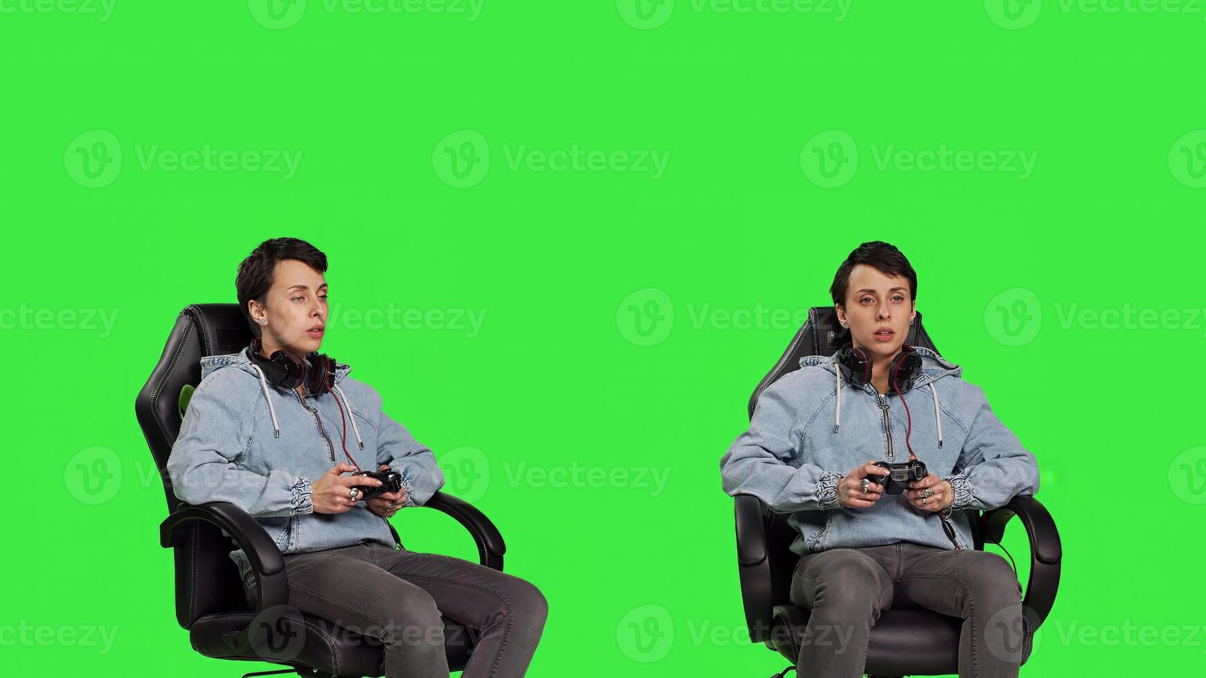 Woman gamer playing online games with controller, sitting in an office chair against greenscreen backdrop. Joyful person having fun with e sport competition, modern gaming setup. Camera B. photo