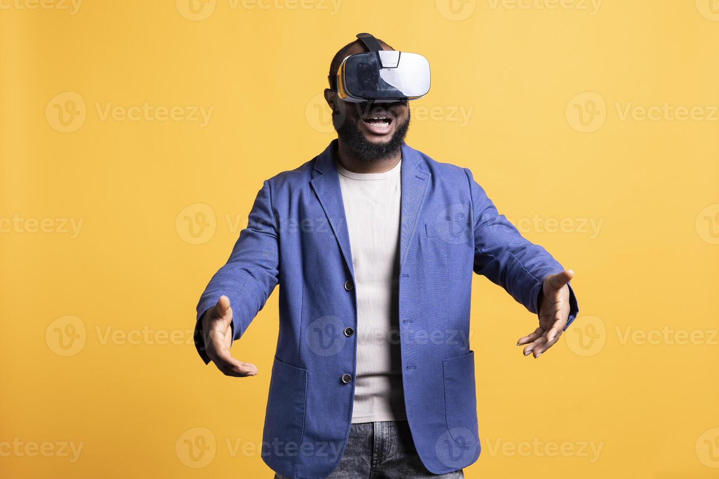 Happy tech fan wearing virtual reality goggles, pretending to hold something. Joyful man delighted to use modern technology VR headset, making tactile hand gesturing, studio background photo