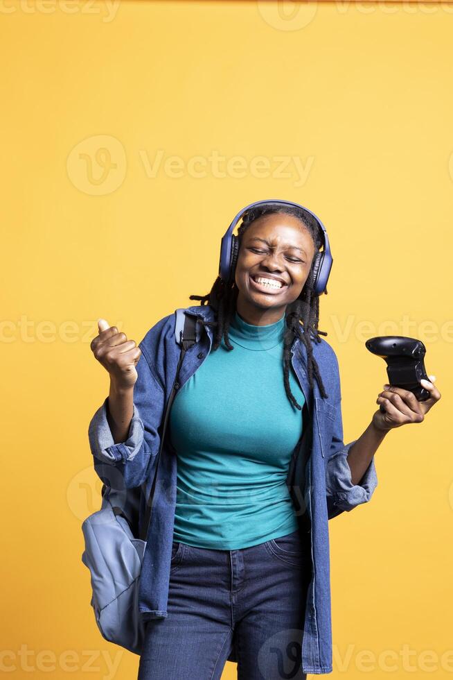 Delighted person playing intense gaming console game, celebrating win, studio background. Ecstatic woman excited after being victorious in videogame, defeating all enemies using controller photo