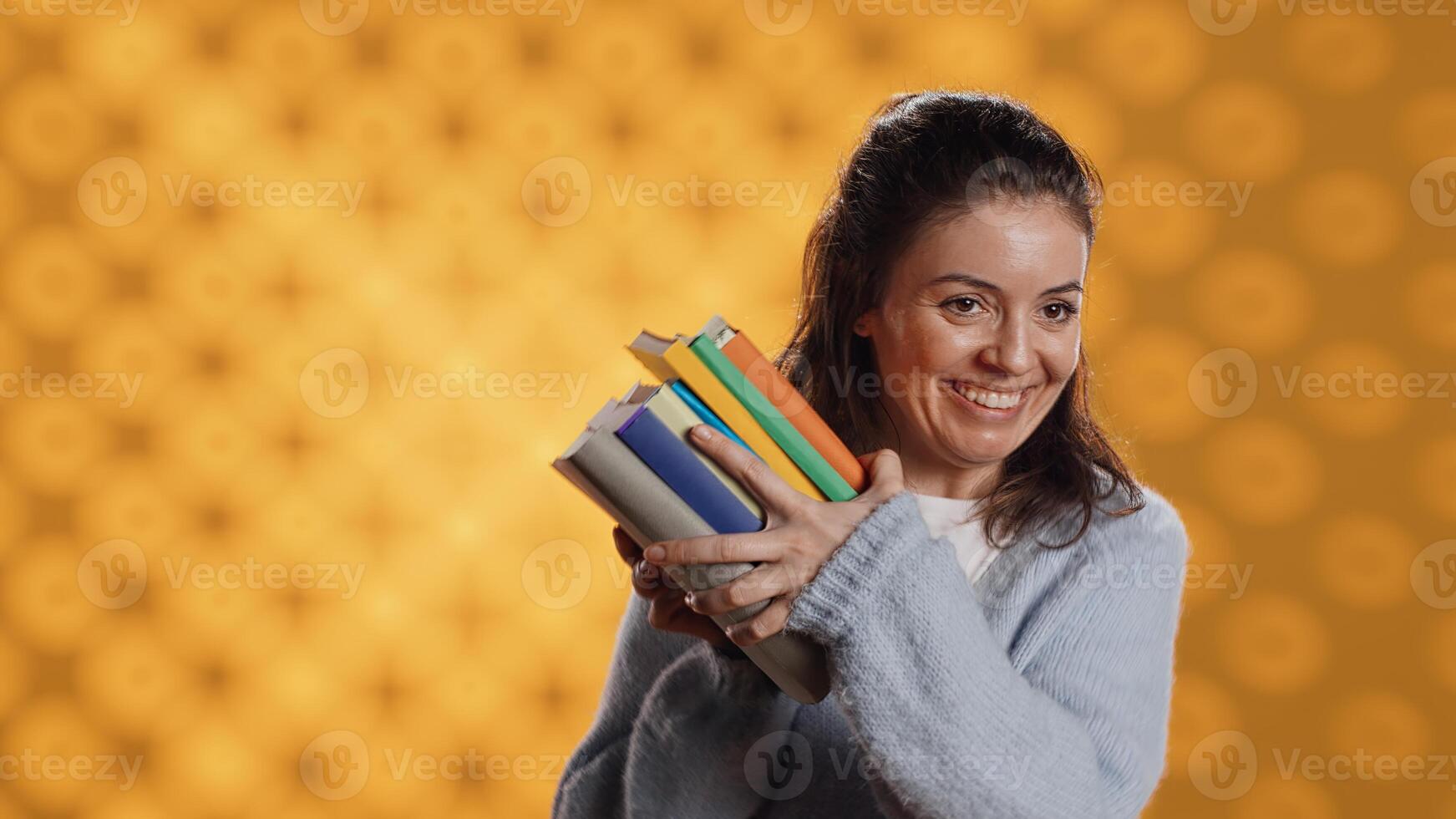 Excited woman delighted about books ordered, treasuring them, isolated over studio background. Euphoric reading enthusiast cherishing stack of novels, feeling lively and overjoyed, camera A photo