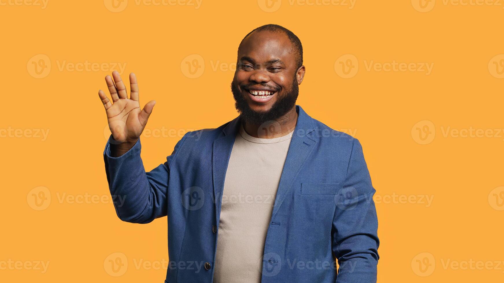 African american man cheerfully doing salutation hand gesture. Portrait of happy BIPOC person raising arm to greet someone, gesturing, isolated over yellow studio background, camera A photo