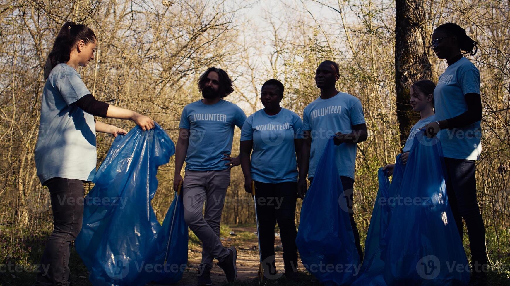 Volunteers group preparing to collect rubbish and junk from the woods, recycling plastic waste and other trash in bags. Environmental activists protecting the nature by picking up garbage. Camera B. photo