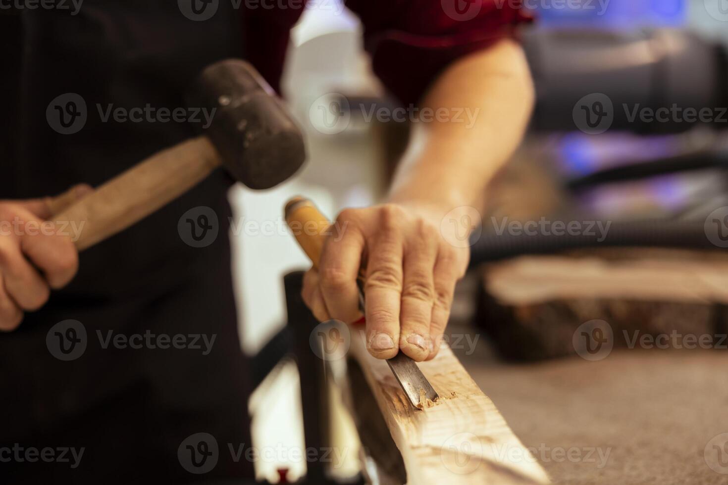 Man carving intricate designs into wood using chisel and hammer in carpentry shop, enjoying diy hobby. Woodworking specialist in studio shaping wooden pieces with tools, making wood art, close up shot photo