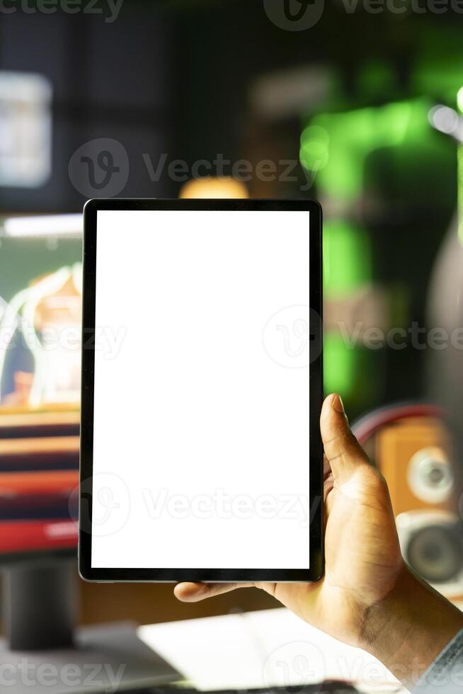 Close up shot of mockup tablet held by man in neon lit apartment while playing videogame on gaming PC. Isolated screen portable device used by person in RGB illuminated home photo
