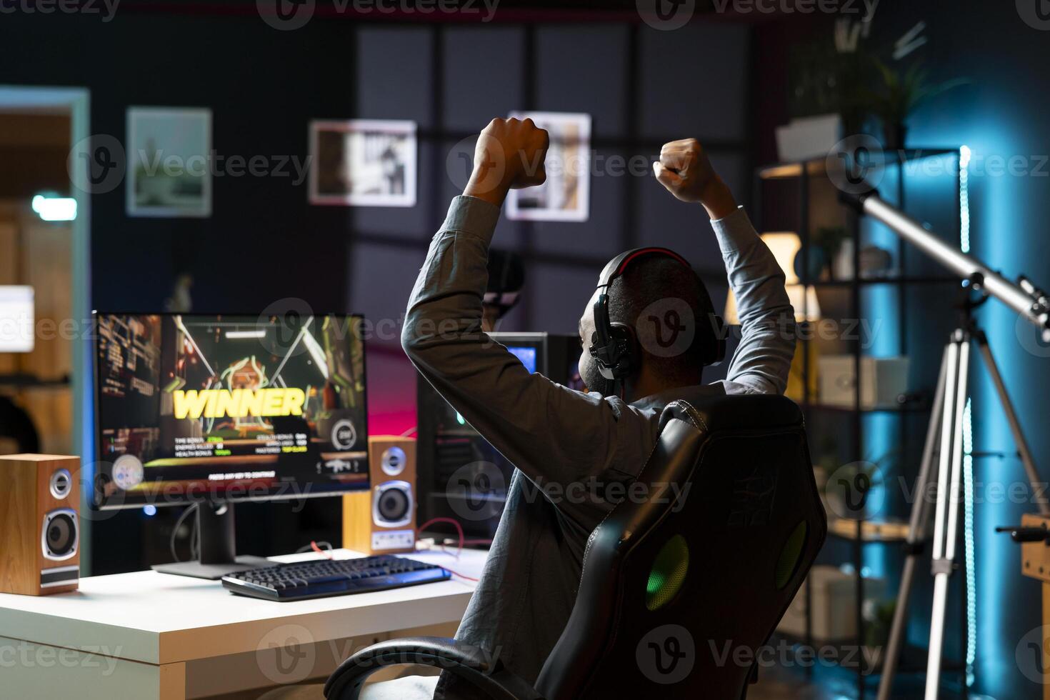 Gamer celebrating winning multiplayer science fiction videogame tournament, playing with friends online. Man happy about gaming championship victory, using headphones to chat with teammates photo