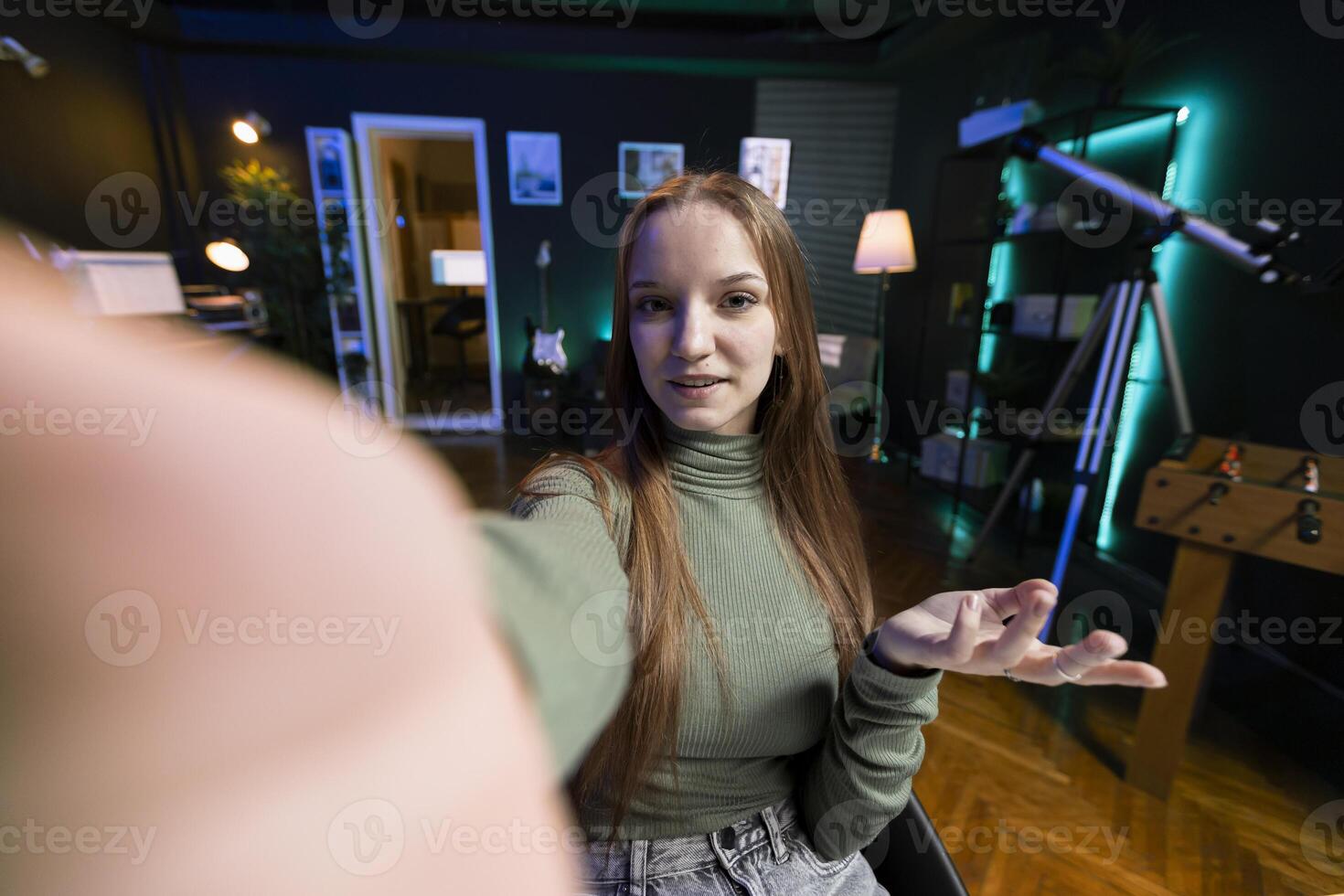 POV of joyous gen Z girl recording introductory with smartphone on selfie stick, inviting viewers to subscribe to channel. Influencer uses selfie camera to film herself connecting with fanbase photo