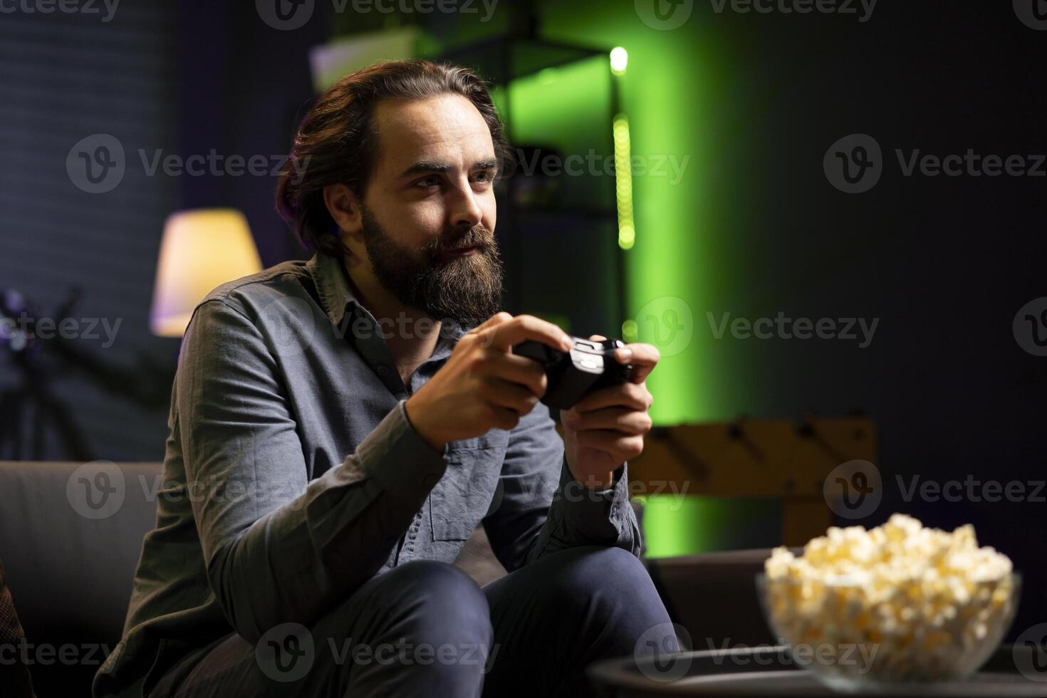 Man holding controller in green neon illuminated apartment, playing videogames. Gamer on couch using joystick to participate in PvP online multiplayer game on console system, relaxing and having fun photo