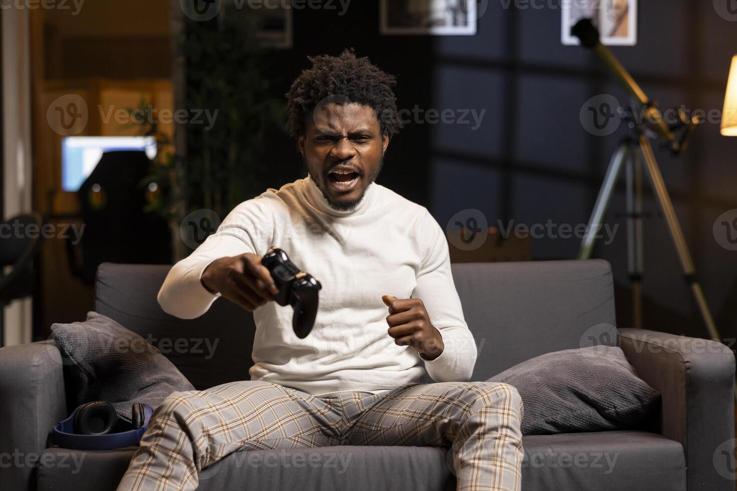 Cheerful gamer releasing pent up emotions after finally defeating all enemies while playing on gaming console. Man congratulating himself after winning videogame, feeling relieved photo