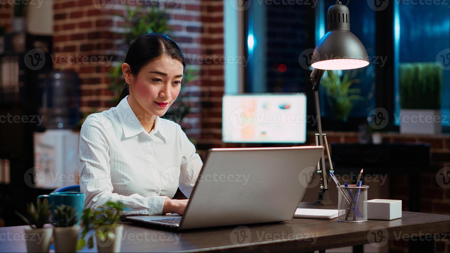 Businesswoman planning marketing project on laptop late at night, using sales statistics on charts. Office employee working on strategy research to create financial development, camera B photo